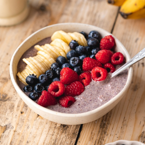 Bowl of healthy instant gluten-free porridge mix – acai, banana, strawberry, buckwheat, and flax seeds.