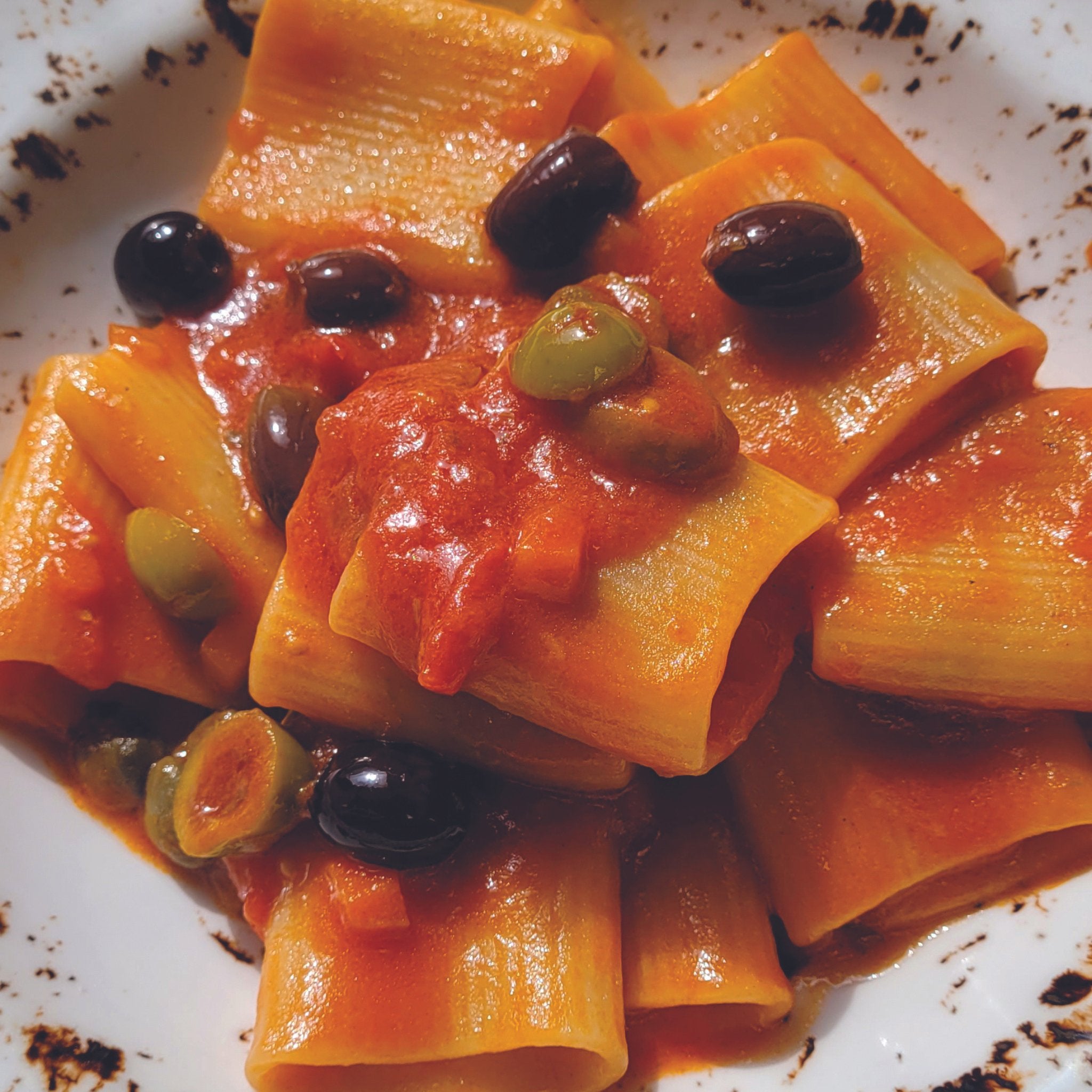 A plate of organic Rigatoni Pasta from Sicily with low gluten index and olives.