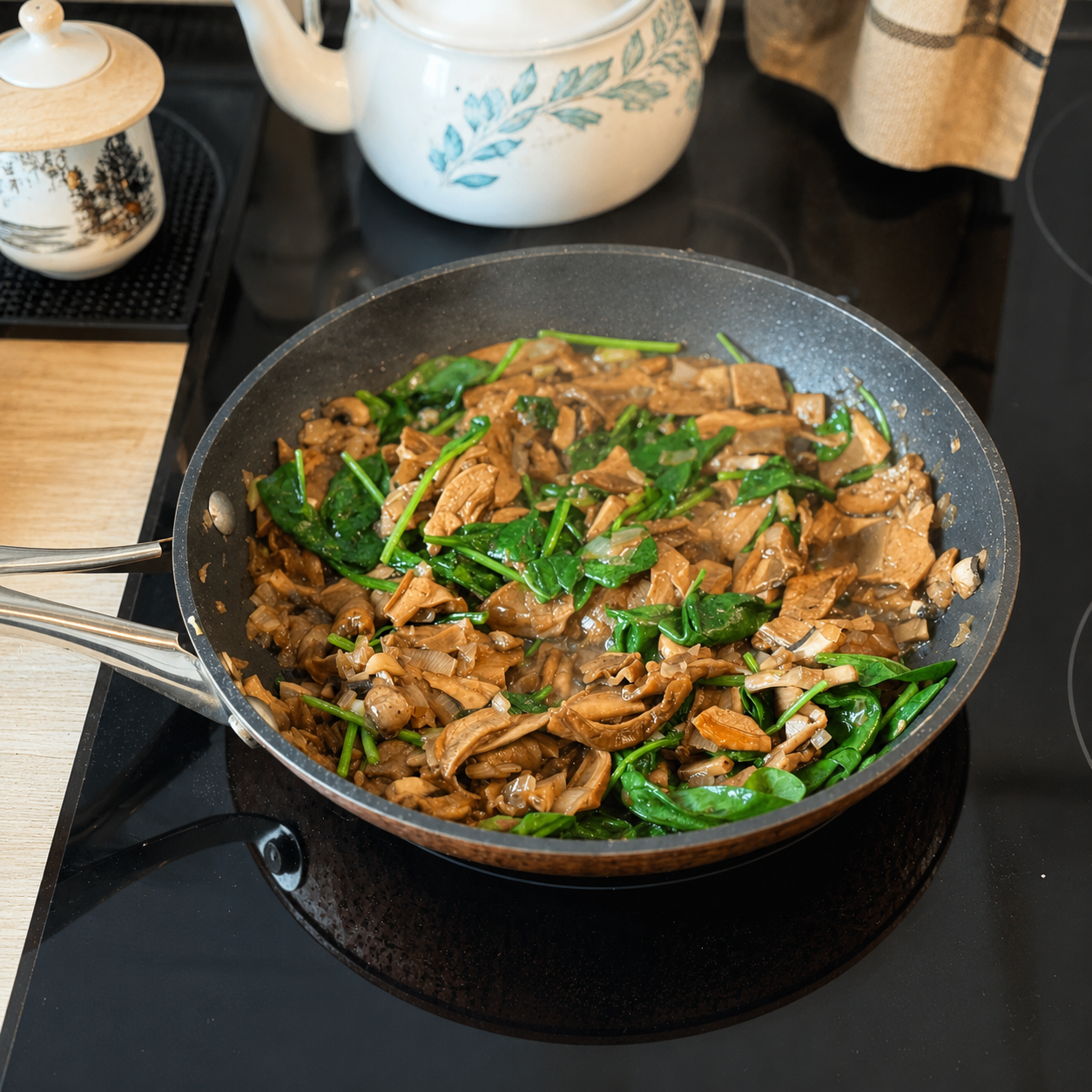 Pan of sautéed porcini mushrooms and spinach cooking on the hob with visible steam